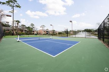a tennis court with two nets on a blue and green court at Lakeside Gardens, Daytona 